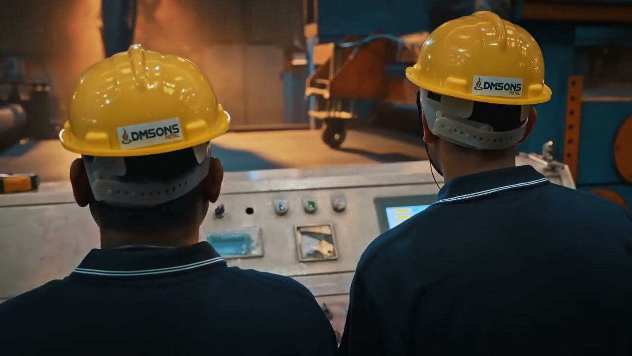 Two Dmsons workers in hard hats at a control panel